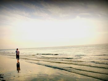 Rear view of man at beach against sky