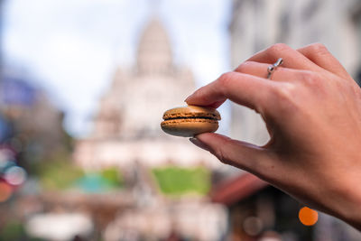 Hand holding a french macaroon cookie on the street of paris