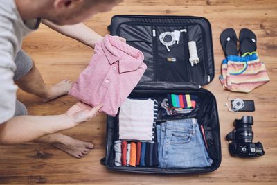 Man packing clothes in luggage at home