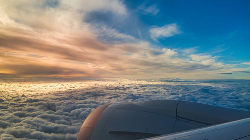 Airplane flying over sea against sky during sunset