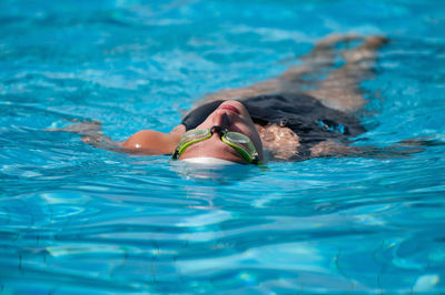 Woman wearing goggles swimming in pool