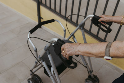 Hands of senior woman holding mobility walker on footpath