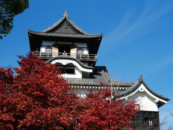 Low angle of japanese castle and autumn leaves against sky