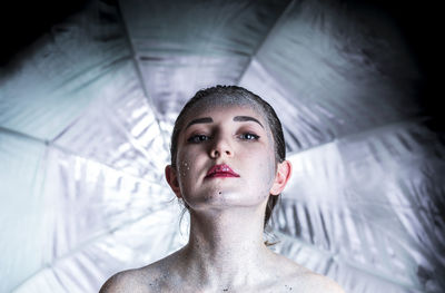 Portrait of young woman covered with glitter against curtain