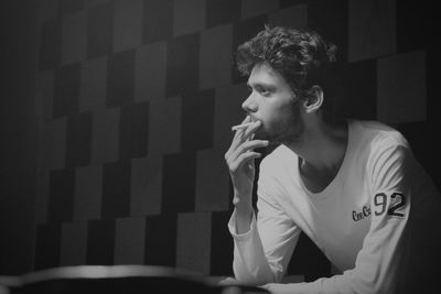 Young man looking away while smoking cigarette