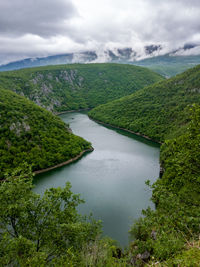 High angle view of river amidst green landscape against sky