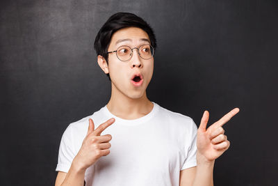 Surprised man gesturing against black background