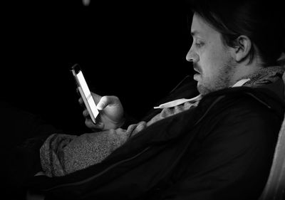 Side view of man using phone in darkroom