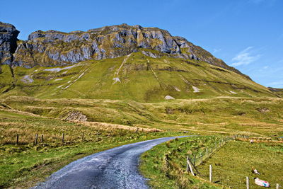 Scenic view of road by mountains against sky