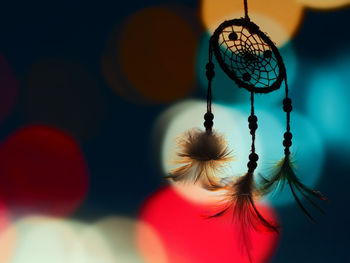 Close-up of dreamcatcher hanging against lens flares