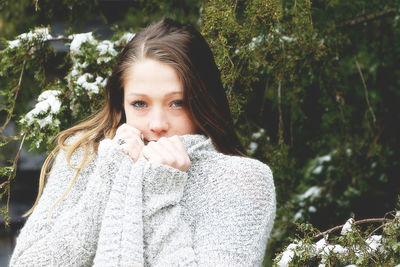 Portrait of beautiful young woman against trees