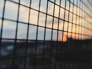 Full frame shot of metal fence against sky during sunset