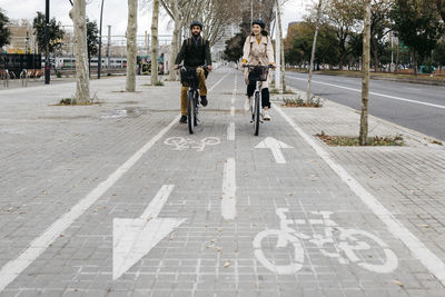 Couple riding e-bikes in the city on bicycle lane