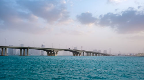 Bridge over sea against sky in city