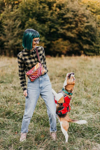 Rear view of woman with dog standing on field