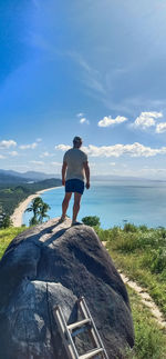 Rear view of man looking at sea against sky