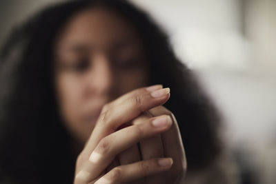 Pensive young woman picking at nails