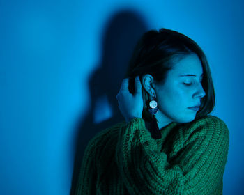 Portrait of young woman looking away against blue wall