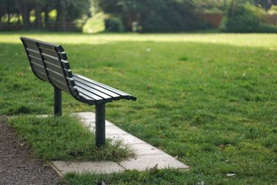 Empty bench on field in park