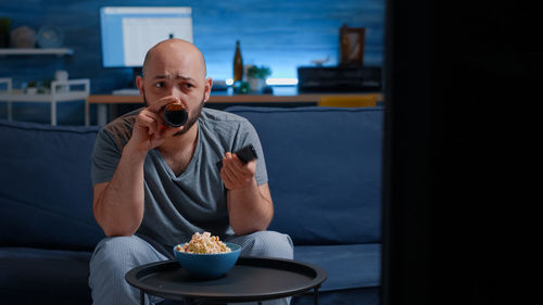 Portrait of young man drinking coffee at home