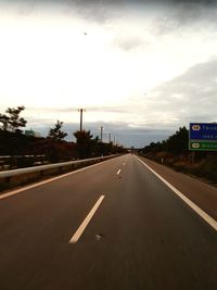 Road sign on highway against sky