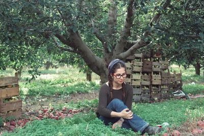 Rear view of woman sitting on tree trunk