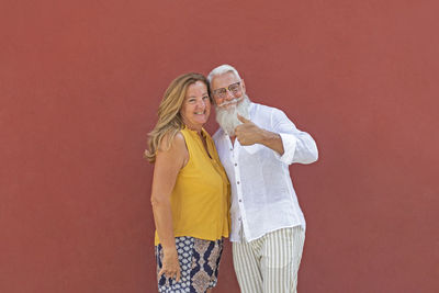 Portrait of smiling woman standing against red wall