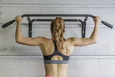 Rear view of young woman exercising at gym