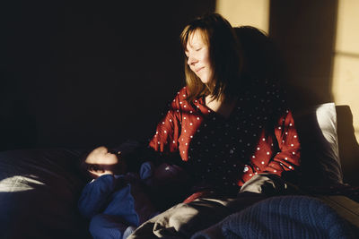 Woman sitting with baby on bed at home