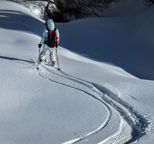 Rear view of girl skiing on snowcapped mountain