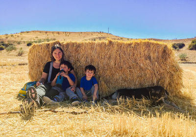 Mother with kids and dog behind straw sheltering from hot weather