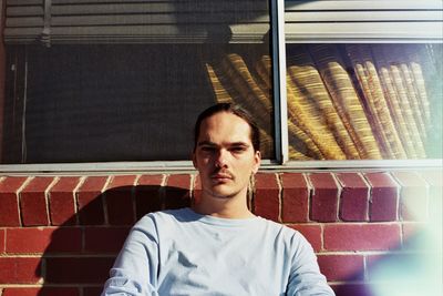 Portrait of young man standing against wall