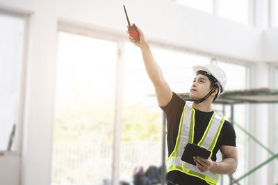 Young man looking away while standing against window