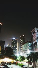 Illuminated city street against clear sky at night