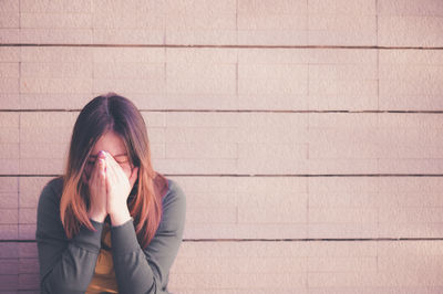 Young woman sitting against wall