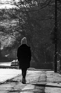 Rear view of woman walking on footpath during winter