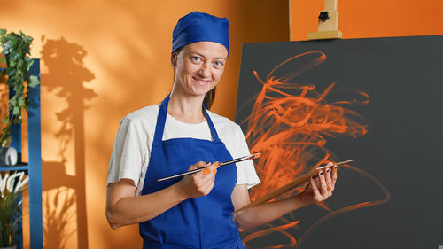 Portrait of smiling young woman standing against black background