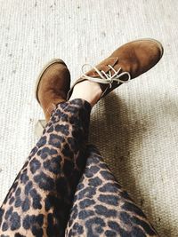 Low section of woman in leopard print sitting on carpet