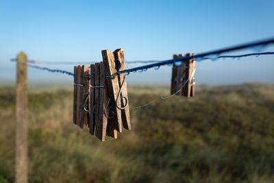 Close-up of clothes peg hanging on rope against fence
