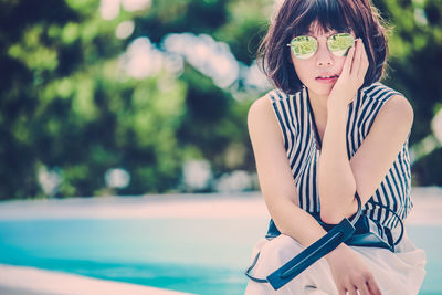 Beautiful young woman sitting by the pool