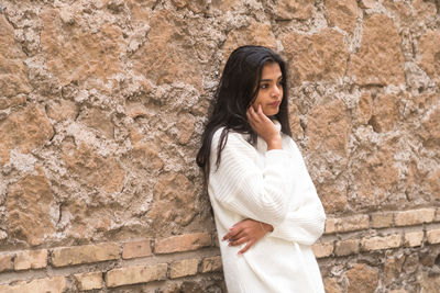 Young woman standing against wall