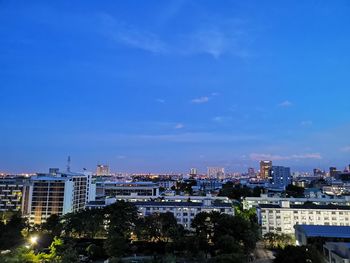 High angle view of illuminated buildings against blue sky