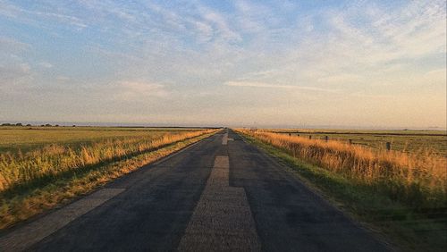 Road amidst field against sky