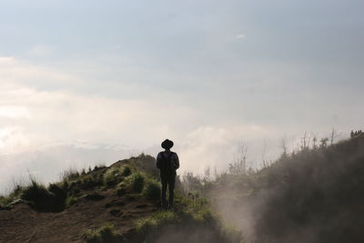 Rear view of man standing on landscape against sky