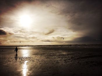 Silhouette person walking on shore against sky