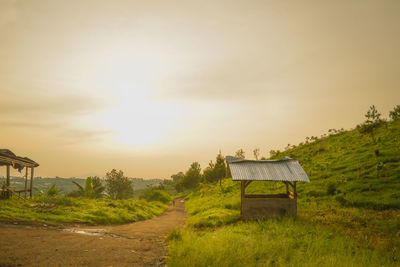 Barn on field against sky during sunset