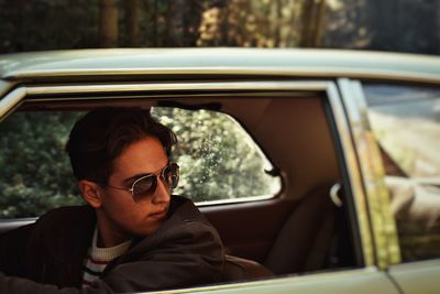 Man wearing sunglasses looking away while sitting in car