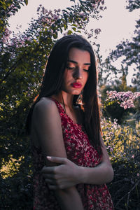 Beautiful woman with pink flower against plant