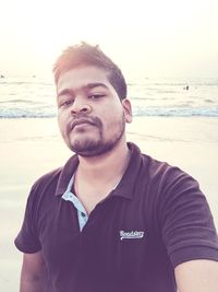 Portrait of man wearing sunglasses at beach against sky