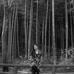 Portrait of woman standing by trees in forest